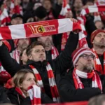 Collectieve groep Union Berlin-supporters met rood-witte sjaals in de tribune.