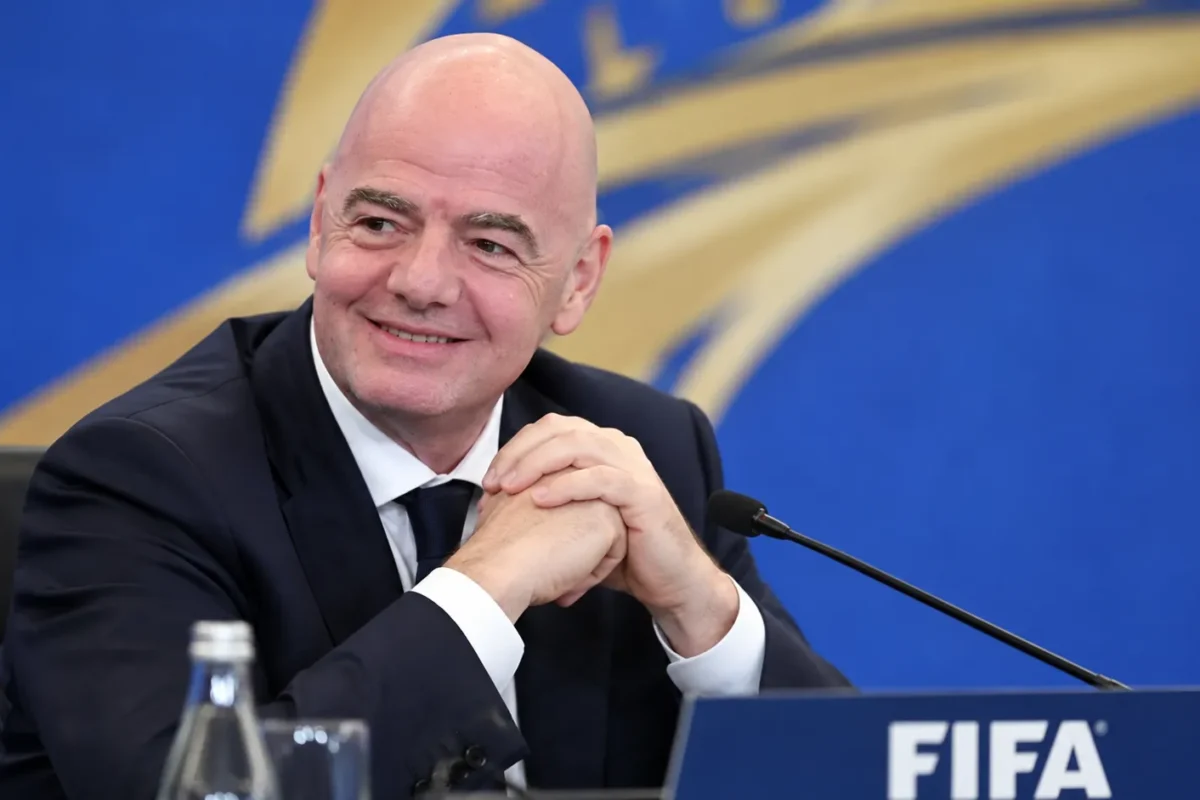 Gianni Infantino in donker pak voor een FIFA-conferentieachtergrond.