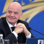 Gianni Infantino in donker pak voor een FIFA-conferentieachtergrond.