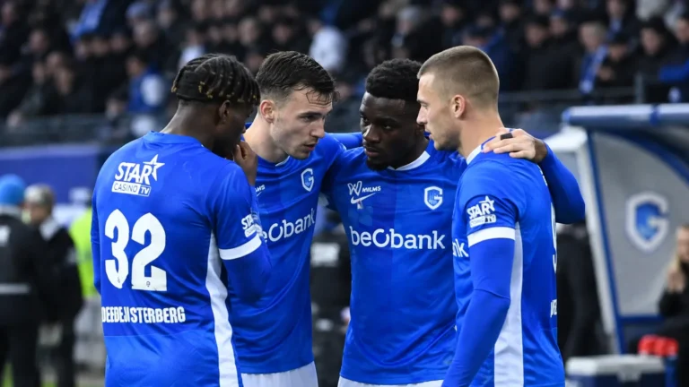 Een groep spelers in blauwe shirts vormt samen een hechte kring op het veld.