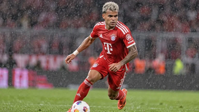 Een Bayern-speler in rood tenue tijdens een regenachtige Bundesliga-wedstrijd.