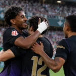 Drie spelers van Barcelona vieren samen aan de cornervlag tijdens een wedstrijd.
