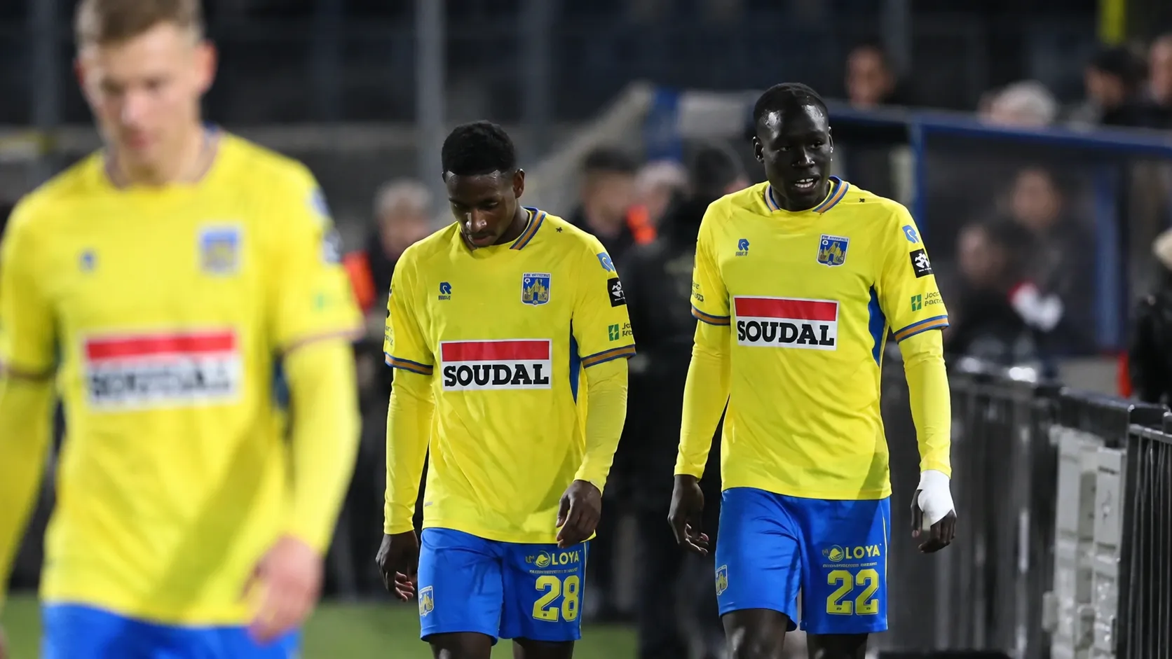 Westerlo-spelers wandelen samen langs de zijlijn na een wedstrijd.
