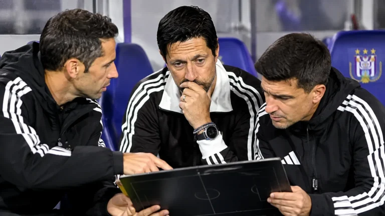 Een groep Anderlecht-stafleden bereidt zich voor in de dug-out.