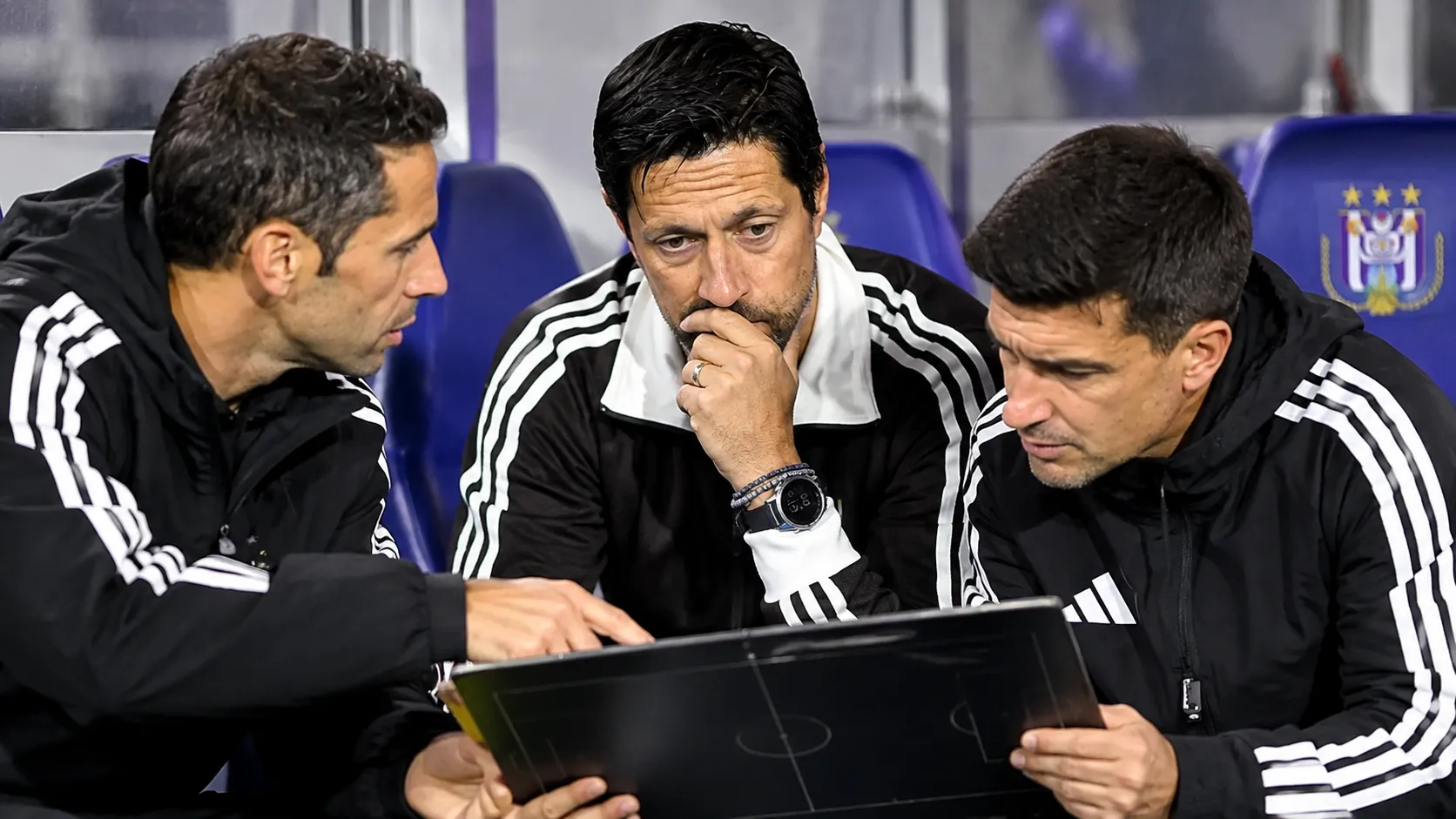 Een groep Anderlecht-stafleden bereidt zich voor in de dug-out.