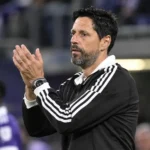 Vitor Bruno applaudisseert langs de zijlijn terwijl Anderlecht-spelers op de achtergrond staan.