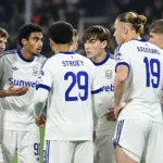 Een groep Anderlecht-spelers verzamelt zich tijdens een wedstrijd in witte tenues.