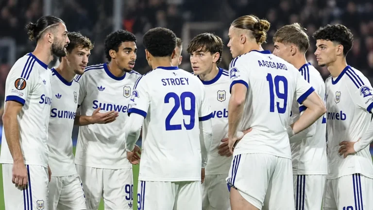 Een groep Anderlecht-spelers verzamelt zich tijdens een wedstrijd in witte tenues.