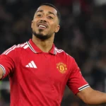 Een speler van Manchester United gebaart op het veld onder stadionlichten.