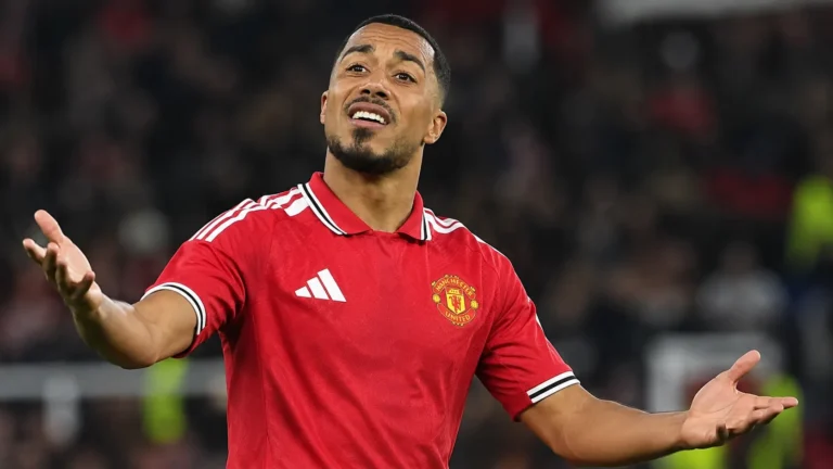 Een speler van Manchester United gebaart op het veld onder stadionlichten.