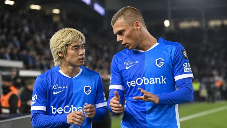 Twee spelers van KRC Genk overleggen naast het veld in blauwe wedstrijdshirts.