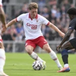 Rein Van Helden van Antwerp in actie met de bal in een wit-rood wedstrijdtenue.