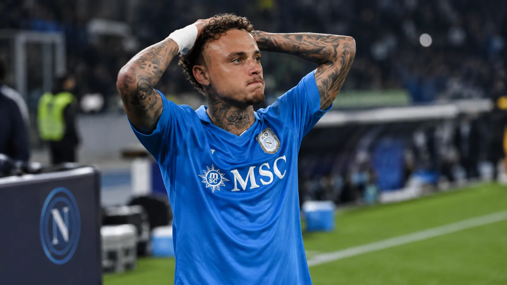 Noa Lang in het blauwe tenue van Napoli aan de zijlijn van een stadion.