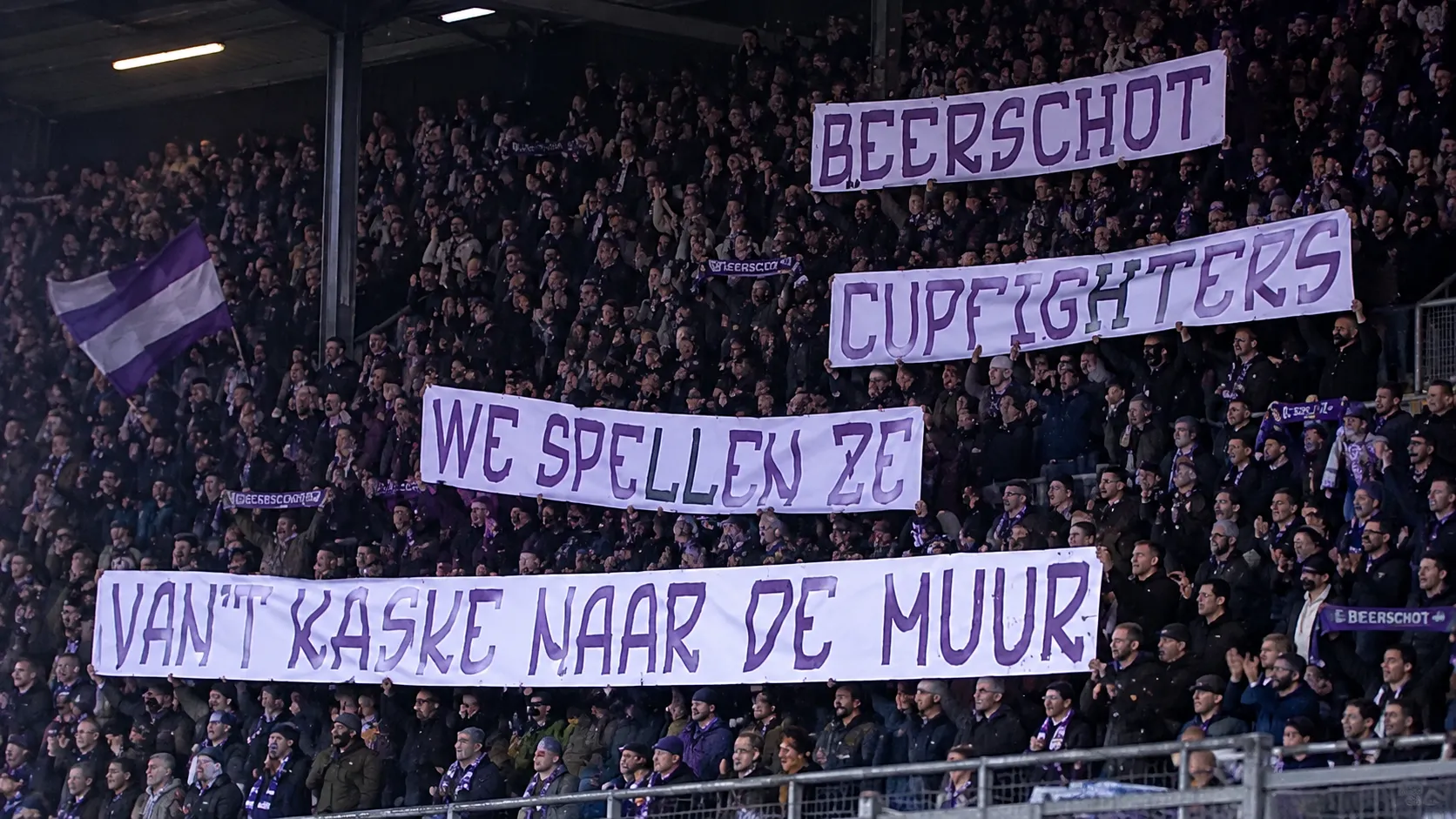 Beerschot-supporters op ’t Kiel met grote witte spandoeken en paarse belettering.