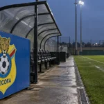 Lege zijlijn van een trainingsveld met een vast DR Congo-embleem op een bord naast de dug-out.