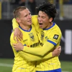 Twee STVV-spelers in gele tenues vieren samen tijdens een bekerwedstrijd.
