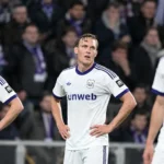 Drie Anderlecht-spelers staan teleurgesteld op het veld na een wedstrijd.