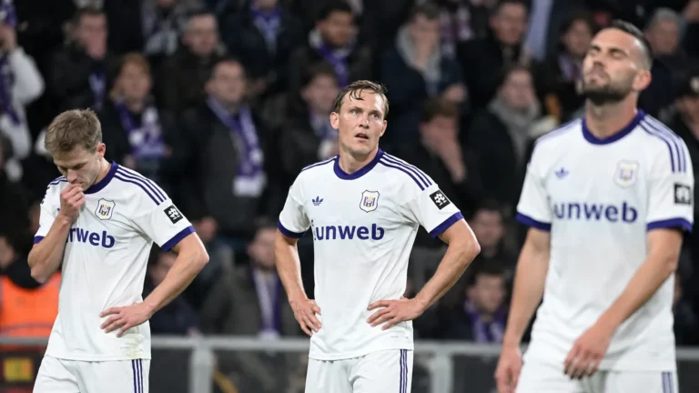 Drie Anderlecht-spelers staan teleurgesteld op het veld na een wedstrijd.