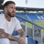 Sergio Ramos in neutrale kledij op een lege tribune met een Getafe-embleem.