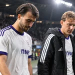 Twee Anderlecht-spelers wandelen na een avondwedstrijd van het veld.