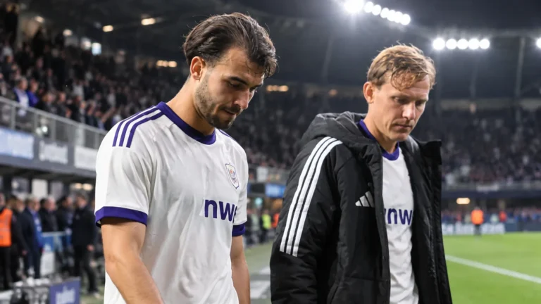 Twee Anderlecht-spelers wandelen na een avondwedstrijd van het veld.