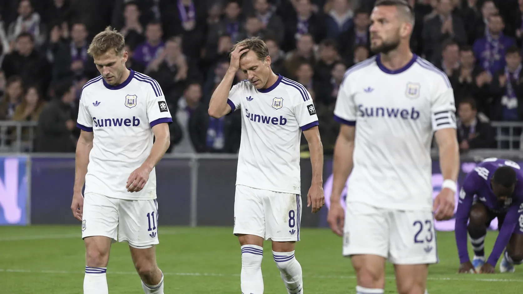 Anderlecht-spelers lopen teleurgesteld op het veld na een bekerwedstrijd.