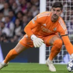 Thibaut Courtois in oranje doelmanstenue van Real Madrid voor het doel.