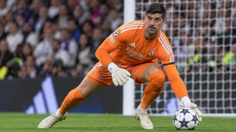 Thibaut Courtois in oranje doelmanstenue van Real Madrid voor het doel.