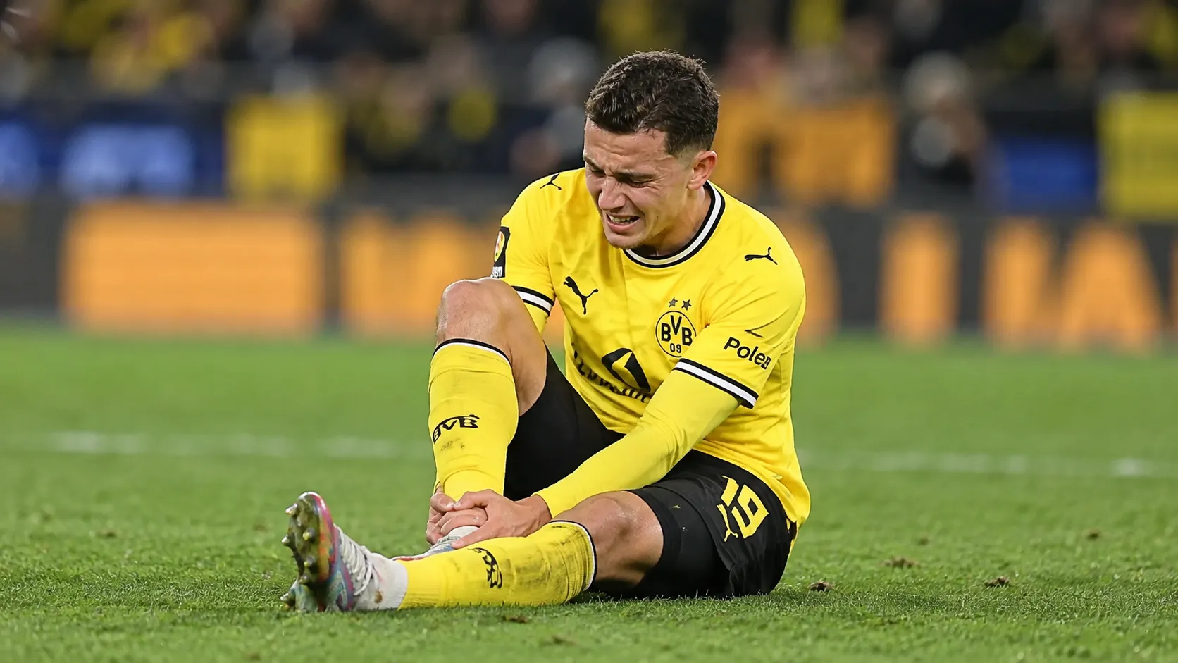 Konstantinos Karetsas van Borussia Dortmund houdt zijn enkel vast op het veld.