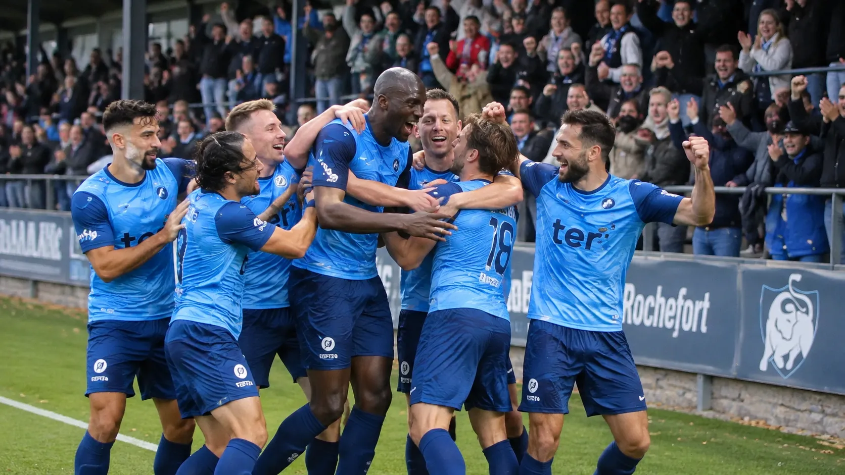 Een groep voetballers in lichtblauwe tenues viert voor een juichende thuistribune.