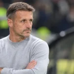 Een niet-spelende clubfiguur van OH Leuven langs de zijlijn van een stadion.