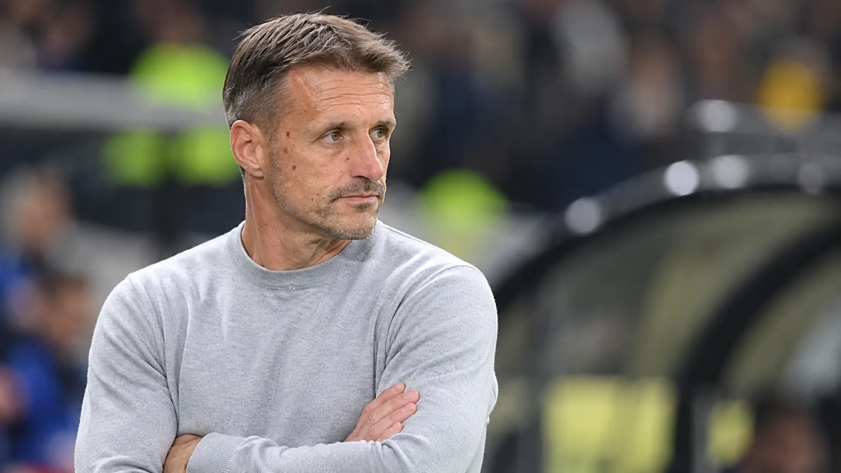 Een niet-spelende clubfiguur van OH Leuven langs de zijlijn van een stadion.