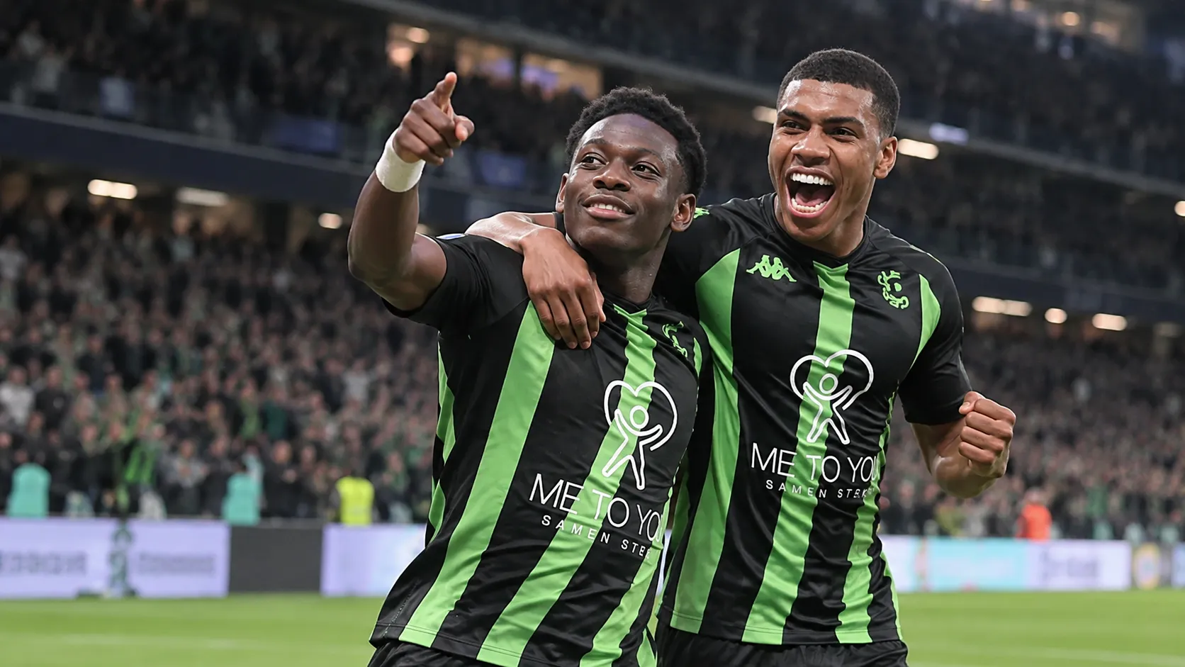 Twee spelers van Cercle Brugge vieren samen een doelpunt op het veld.