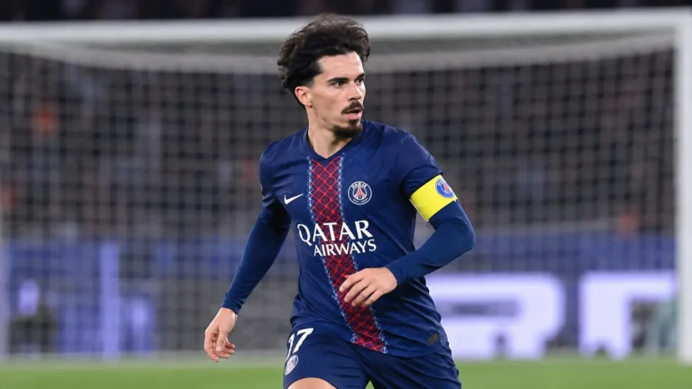 Vitinha in PSG-tenue op een verlicht voetbalveld met een doelnet op de achtergrond.