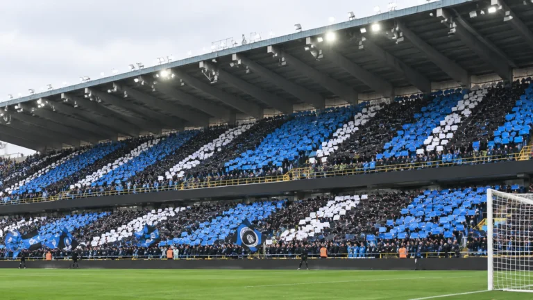 Collectieve Club Brugge-supporters met blauw-zwarte kaarten op de tribune.