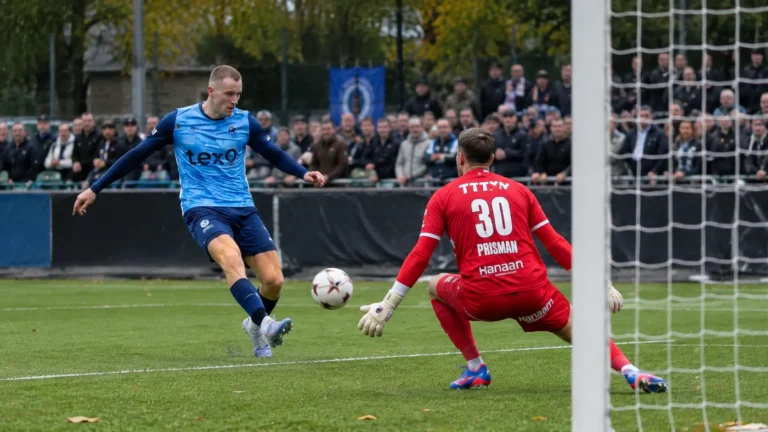 Een speler in blauw en een doelman in rood tijdens een nieuw spelmoment voor doel.