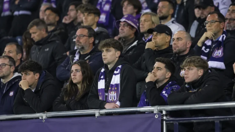Een groep teleurgestelde Anderlecht-supporters op de tribune met een paars-witte sjaal.