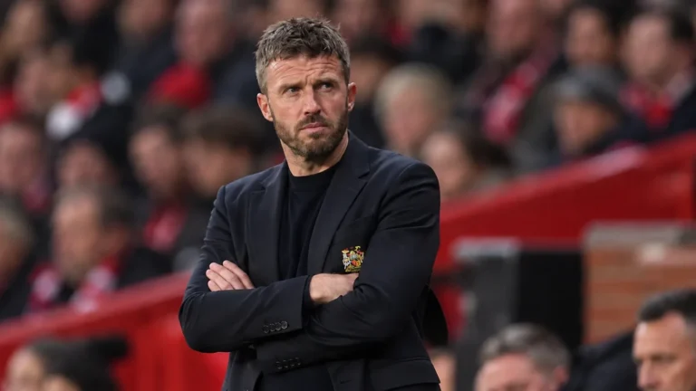 Een Manchester United-trainer staat geconcentreerd langs de zijlijn tijdens een wedstrijd.