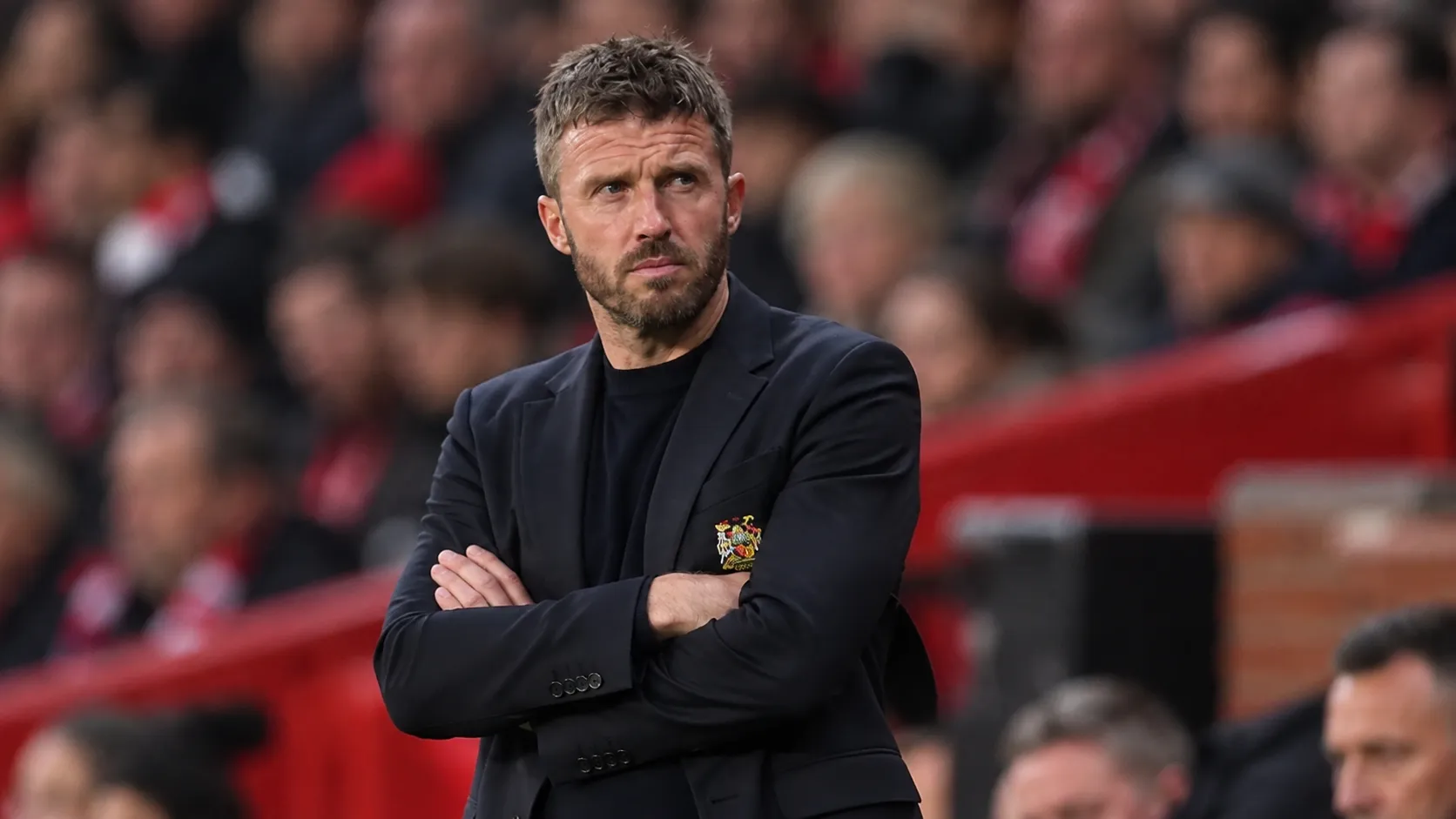 Een Manchester United-trainer staat geconcentreerd langs de zijlijn tijdens een wedstrijd.