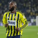 Romelu Lukaku warmt op in een geel-blauw gestreept voetbalshirt op het veld.