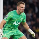 Een Tottenham-doelman in groen tenue reageert tijdens een wedstrijdmoment.