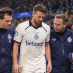Brandon Mechele loopt met twee Club Brugge-medewerkers langs de zijlijn tijdens een wedstrijdonderbreking.