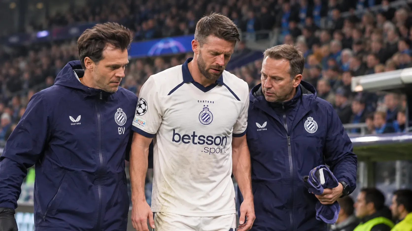 Brandon Mechele loopt met twee Club Brugge-medewerkers langs de zijlijn tijdens een wedstrijdonderbreking.