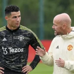 Een speler en een staflid van Manchester United in gesprek op het trainingsveld.