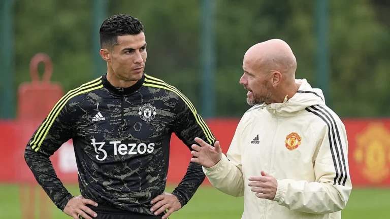 Een speler en een staflid van Manchester United in gesprek op het trainingsveld.