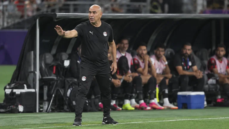 Egyptische bondscoach staat geconcentreerd aan de zijlijn voor de spelersbank.