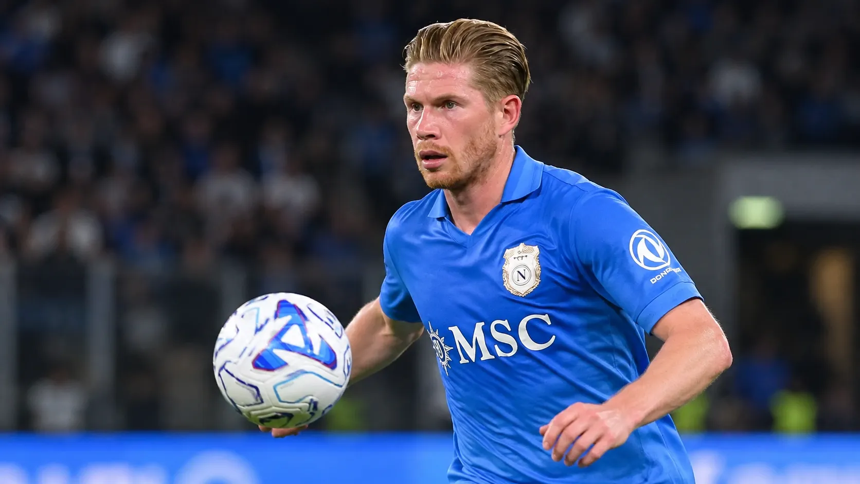 Kevin De Bruyne in blauw Napoli-tenue tijdens een wedstrijdmoment met de bal.