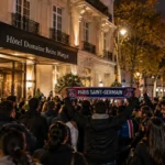 Een groep PSG-supporters met sjaals bij een hotel in Parijs tijdens de nacht.