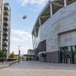 Een rugbybal hangt in de lucht naast het lege Gtech Community Stadium.