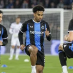 Club Brugge-spelers in blauw-zwarte shirts tijdens een geconcentreerde opwarming op het veld.